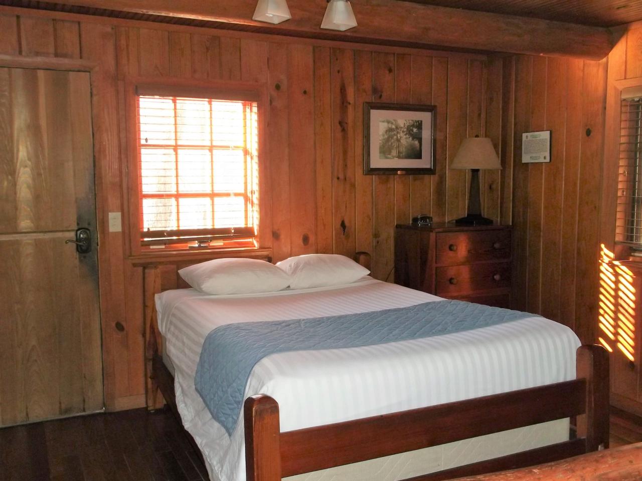 A view of the bedroom area in the studio cabin 17 including a bed, dresser and the cabin front door